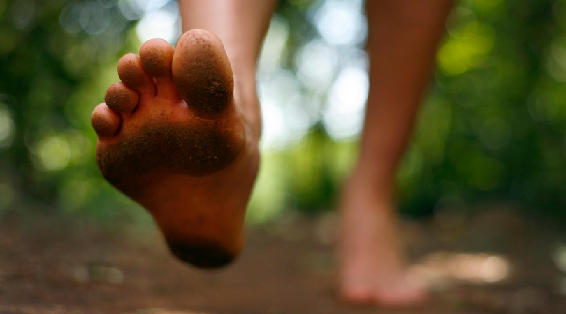 runner walking barefoot in the woods