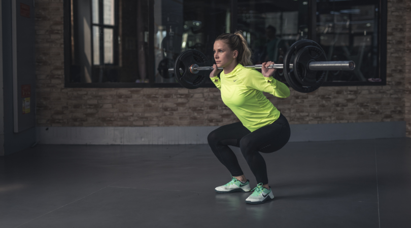 runner squatting with weight to keep healthy tendons